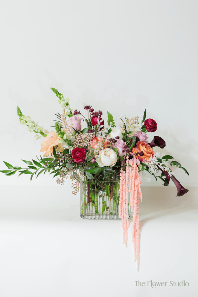 This striking and vibrant flower arrangement is a breathtaking blend of rich hues, soft textures, and elegant foliage.
