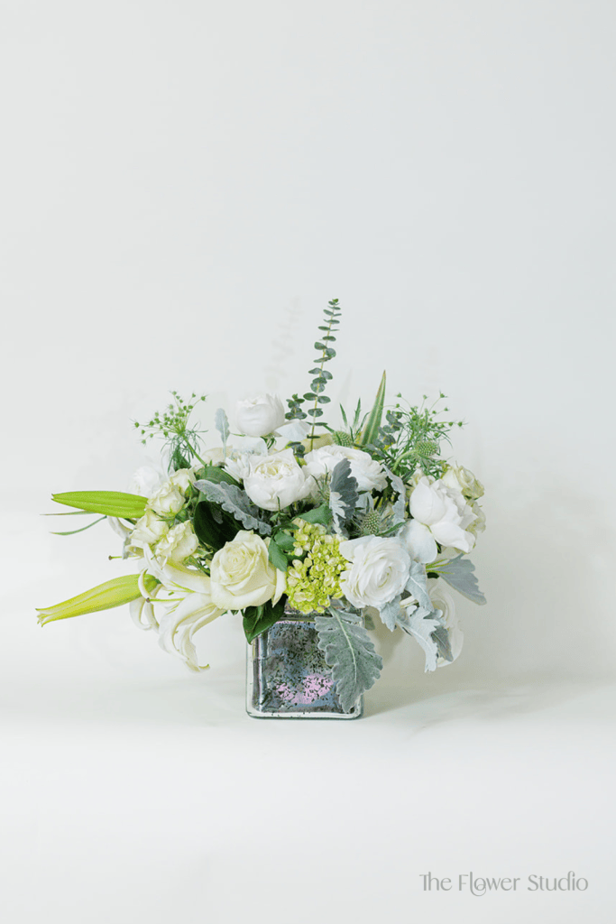 Elegant, fresh, and full of grace, this stunning arrangement brings together soft whites and subtle greens for a truly refined look.