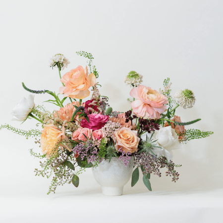 Elegance meets vibrant charm in this breathtaking floral arrangement, showcasing a delicate blend of soft peaches, purples, and whites.