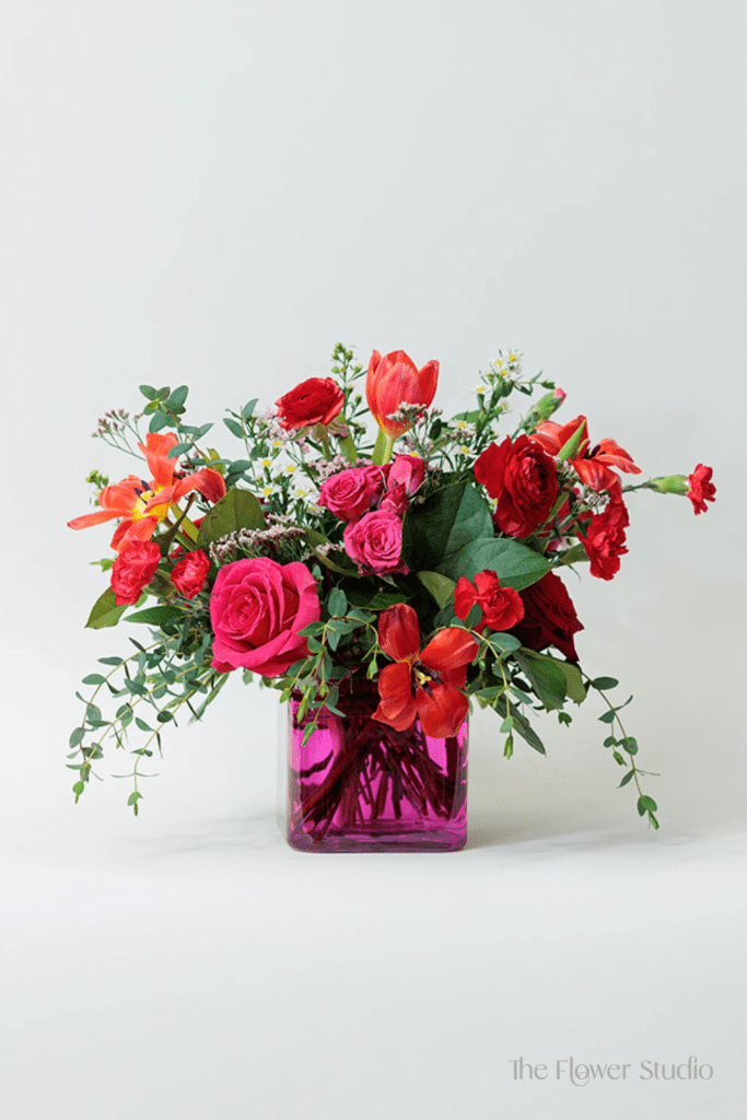 This vibrant and romantic flower arrangement is a stunning blend of rich reds, soft pinks, and fresh greens, creating a lively and energetic design.