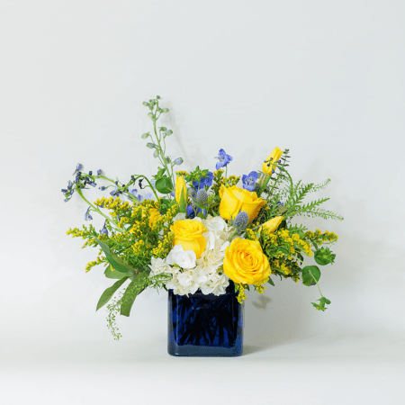 Bright, cheerful, and full of energy, this stunning arrangement is a celebration of bold yellow and calming blue tones.