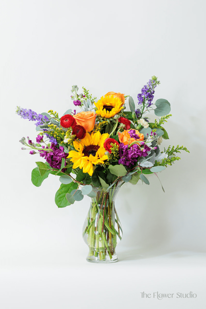 This vibrant and cheerful flower arrangement features a stunning combination of colors and textures.