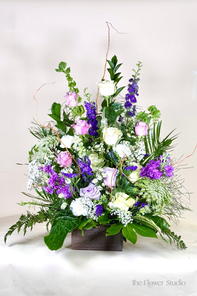 Express heartfelt condolences with this elegant sympathy arrangement, thoughtfully designed in soothing shades of purple, lavender, and white.
