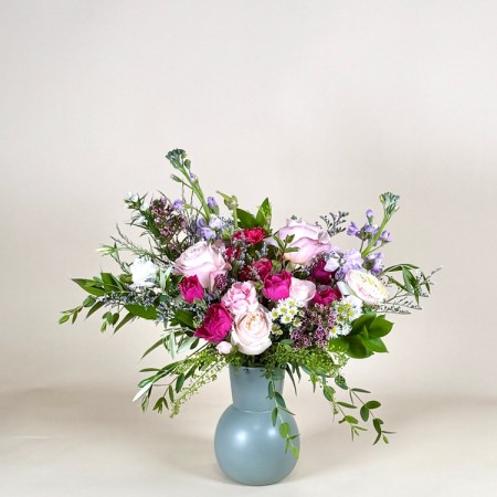 A stunning compact floral arrangement designed with a delicate blend of soft pink and lavender blooms, creating a look that’s both elegant and charming.