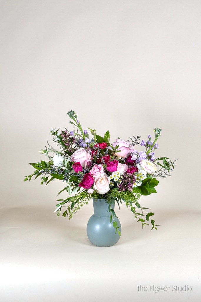 A stunning compact floral arrangement designed with a delicate blend of soft pink and lavender blooms, creating a look that’s both elegant and charming.
