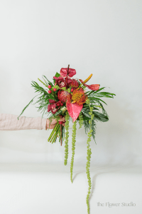 This tropical-colored hand-tied bouquet is a vibrant celebration of bold hues and exotic blooms, designed to bring an energizing, tropical flair to any occasion.